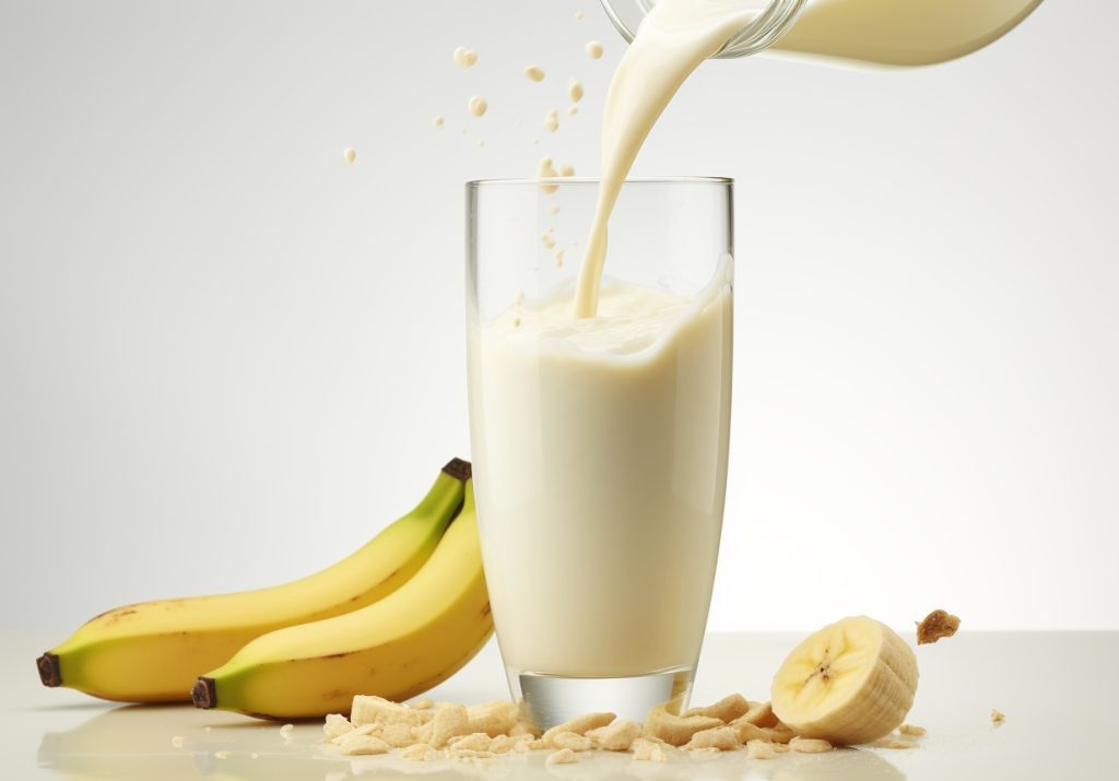 A creamy Soyful Apple Banana Bliss smoothie in a tall glass, accompanied by banana and a splash of soya milk on a minimalist backdrop.